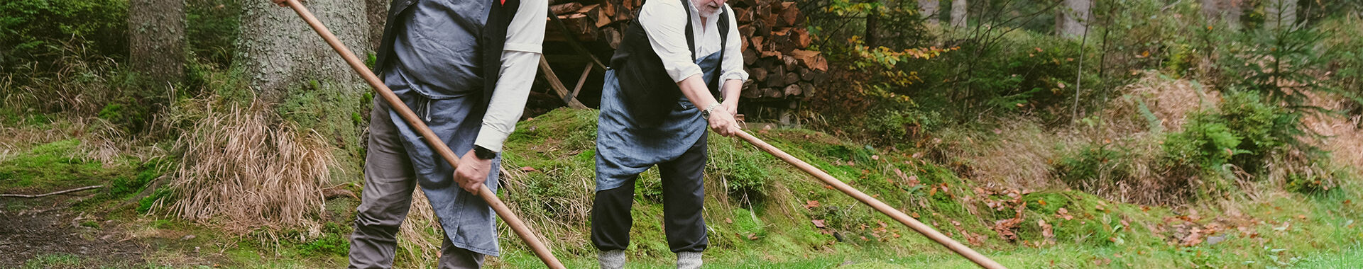 Zwei Arbeiter ziehen in traditioneller Arbeitskleidung Holz aus dem Schwemmkanal