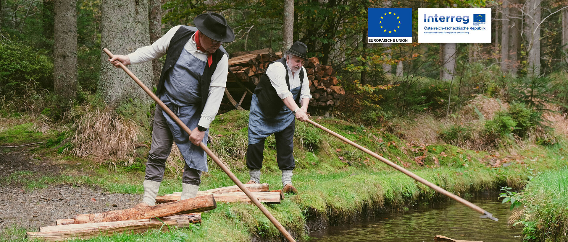 Zwei Holzschwemmen in traditioneller Kleidung schwemmen in einem Wasserkanal Holz.